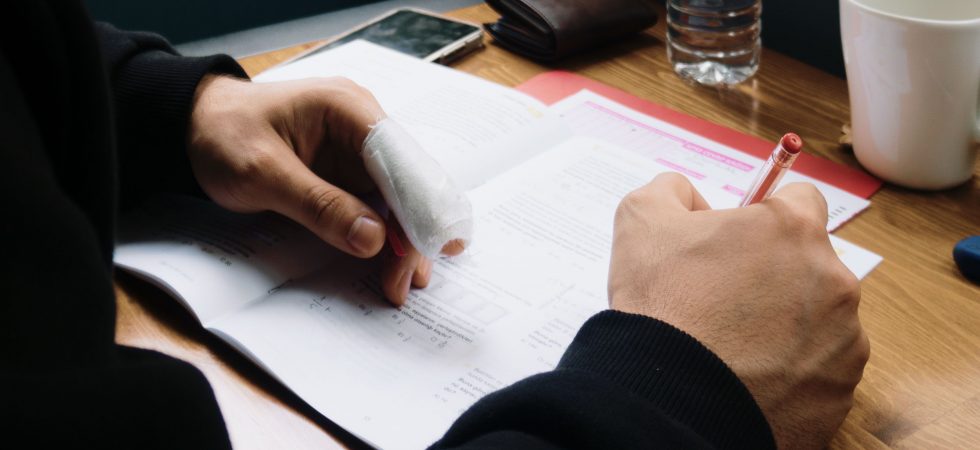 man with an injured finger signing a document